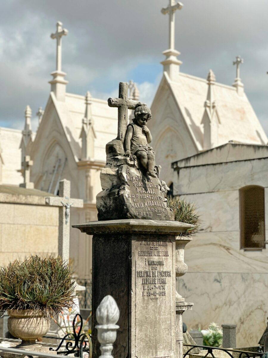 A stone cherub statue adorns a grave in Porto's Agramonte Cemetery, Portugal.